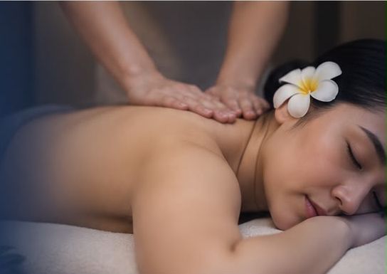 A guest relaxing during a back massage, a white frangipani in her hair